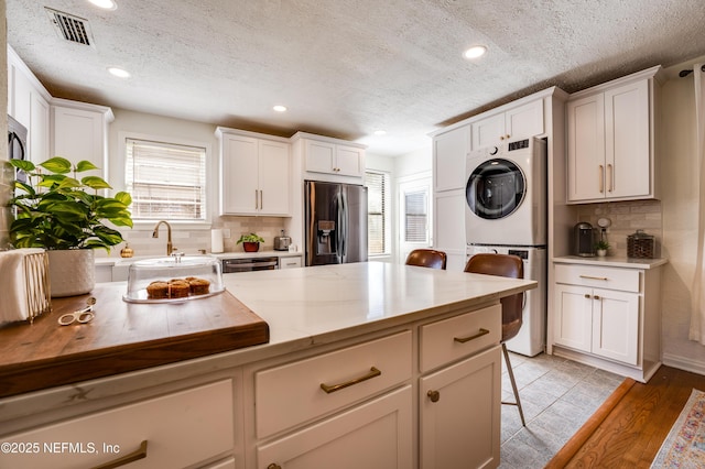 4818 Astral St, Jacksonville, FL 32205 - kitchen with stainless steel appliances, stacked washing machine and dryer, tasteful backsplash, a textured ceiling, and a breakfast bar area