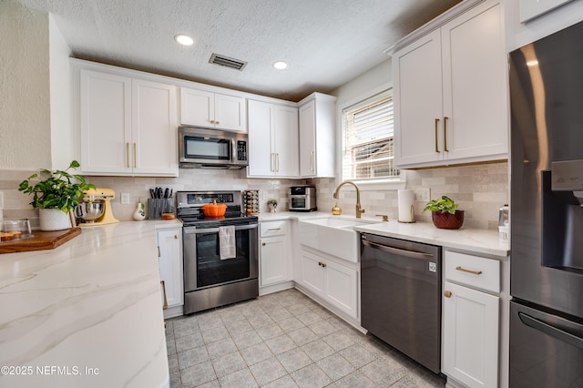 4818 Astral St, Jacksonville, FL 32205 - kitchen with appliances with stainless steel finishes, tasteful backsplash, white cabinets, a textured ceiling, and recessed lighting