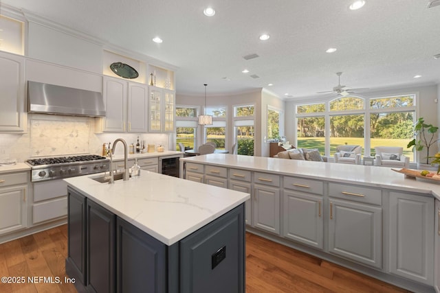 1614 Sheffield Park Ct, Jacksonville, FL 32225 - kitchen with wall chimney range hood, wine cooler, stainless steel gas stovetop, a kitchen island with sink, and recessed lighting