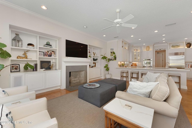 1614 Sheffield Park Ct, Jacksonville, FL 32225 - living room with a ceiling fan, crown molding, recessed lighting, light wood-style floors, and a fireplace with flush hearth