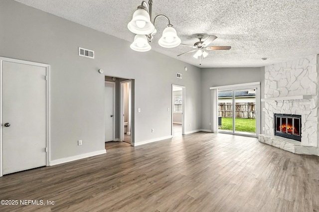6719 Newgate Cir E, Jacksonville, FL 32244 - unfurnished living room featuring a ceiling fan, a textured ceiling, a stone fireplace, wood finished floors, and a chandelier