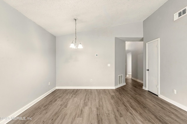 6719 Newgate Cir E, Jacksonville, FL 32244 - empty room with vaulted ceiling, wood finished floors, a chandelier, and a textured ceiling