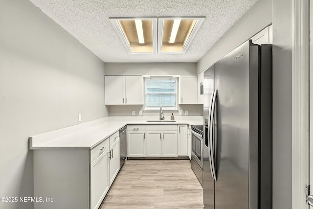 6719 Newgate Cir E, Jacksonville, FL 32244 - kitchen featuring stainless steel appliances, a textured ceiling, light wood-style floors, light countertops, and white cabinets
