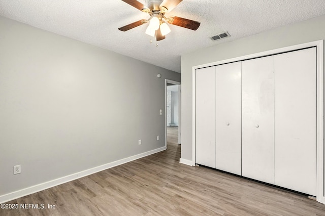 6719 Newgate Cir E, Jacksonville, FL 32244 - unfurnished bedroom featuring light wood-style floors, a closet, a textured ceiling, and a ceiling fan
