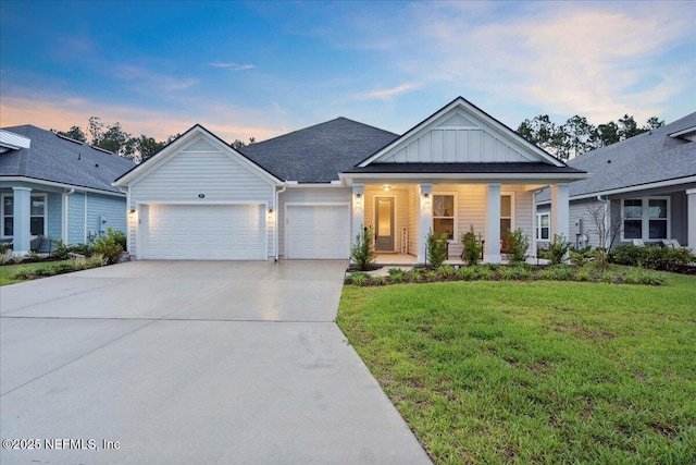 227 Wind Chime Ln, Saint Augustine, FL 32095 - view of front of house with board and batten siding, an attached garage, a lawn, concrete driveway, and covered porch
