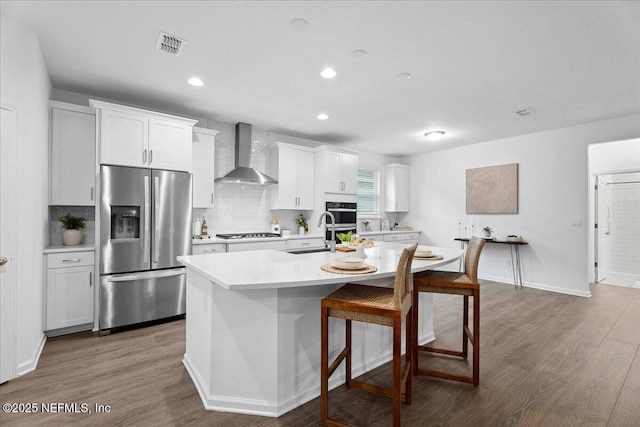 227 Wind Chime Ln, Saint Augustine, FL 32095 - kitchen with appliances with stainless steel finishes, wall chimney range hood, dark wood finished floors, light countertops, and recessed lighting