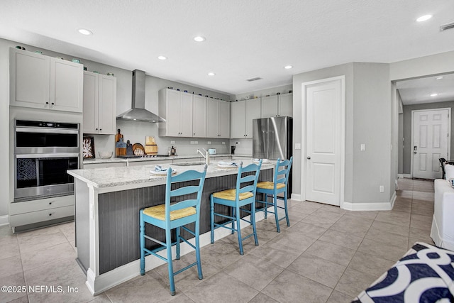 62 Seaside Vista Ct, Saint Augustine, FL 32084 - kitchen with wall chimney exhaust hood, appliances with stainless steel finishes, a kitchen bar, recessed lighting, and an island with sink