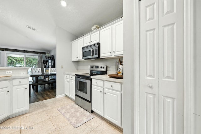 145 E Blackjack Branch Way, Saint Johns, FL 32259 - kitchen with appliances with stainless steel finishes, light countertops, light tile patterned flooring, white cabinets, and vaulted ceiling