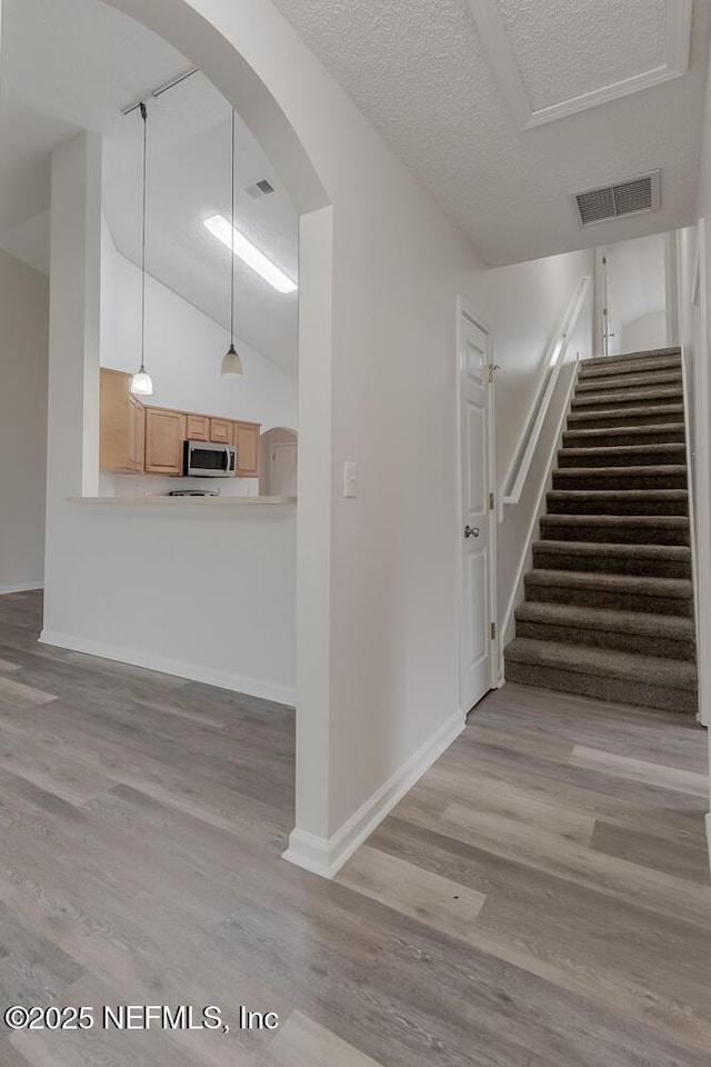 1203 Summer Springs Dr, Middleburg, FL 32068 - stairs featuring wood finished floors, arched walkways, vaulted ceiling, and a textured ceiling