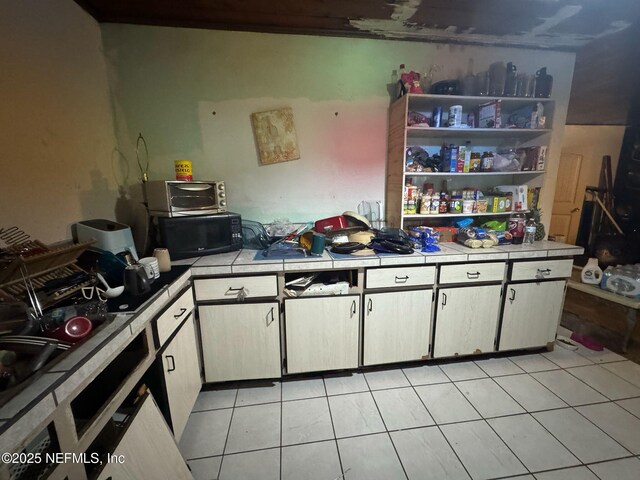 511 Clearview Dr, Cocoa, FL 32927 - kitchen featuring tile counters, black microwave, light tile patterned floors, and white cabinets