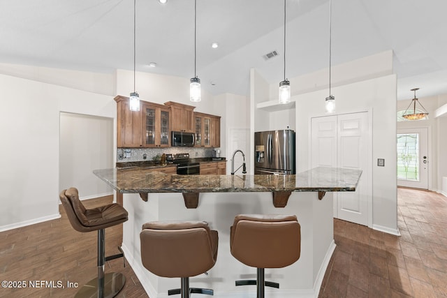 213 Seamist Ct, Ponte Vedra Beach, FL 32082 - kitchen featuring stainless steel appliances, brown cabinetry, a breakfast bar, decorative backsplash, and glass insert cabinets