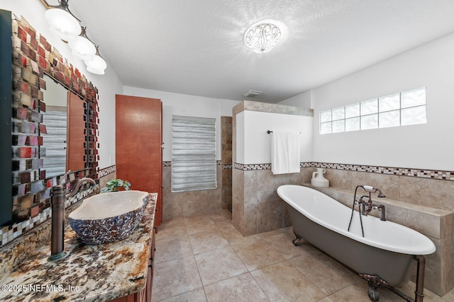 213 Seamist Ct, Ponte Vedra Beach, FL 32082 - bathroom featuring tile walls, a freestanding bath, tile patterned flooring, vanity, and a textured ceiling