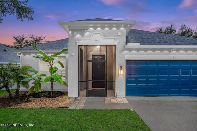 25122 Chipshot Ct, Sorrento, FL 32776 - exterior entry at dusk with roof with shingles, an attached garage, stucco siding, and driveway