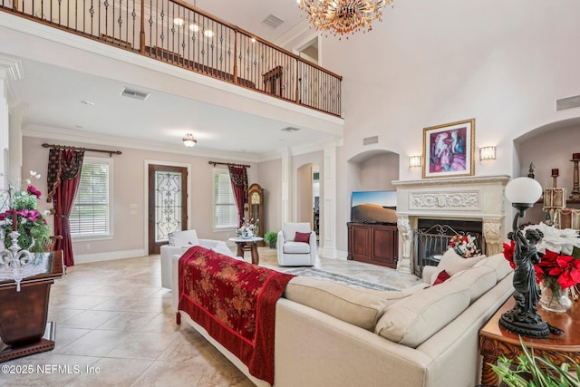 2645 Oakgrove Ave, Saint Augustine, FL 32092 - tiled living room featuring crown molding, a towering ceiling, arched walkways, a fireplace, and a chandelier