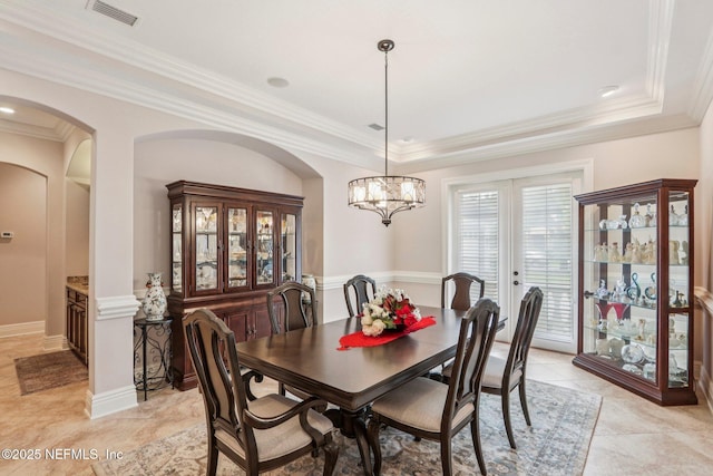 2645 Oakgrove Ave, Saint Augustine, FL 32092 - dining room featuring french doors, arched walkways, a raised ceiling, a chandelier, and ornamental molding