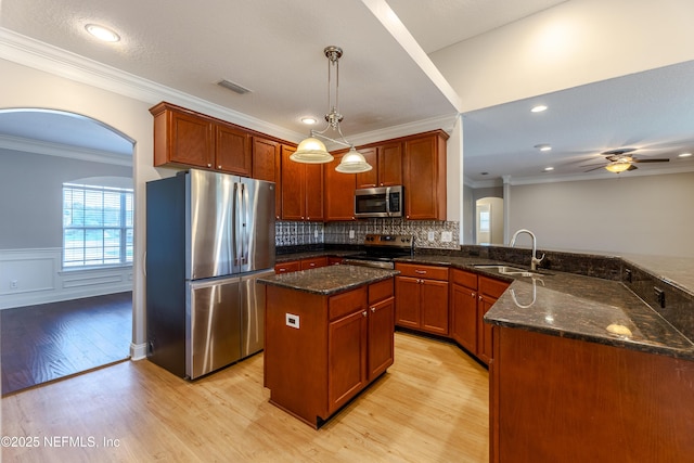 1300 Coopers Hawk Way, Middleburg, FL 32068 - kitchen with appliances with stainless steel finishes, light wood-style flooring, dark stone counters, a peninsula, and tasteful backsplash