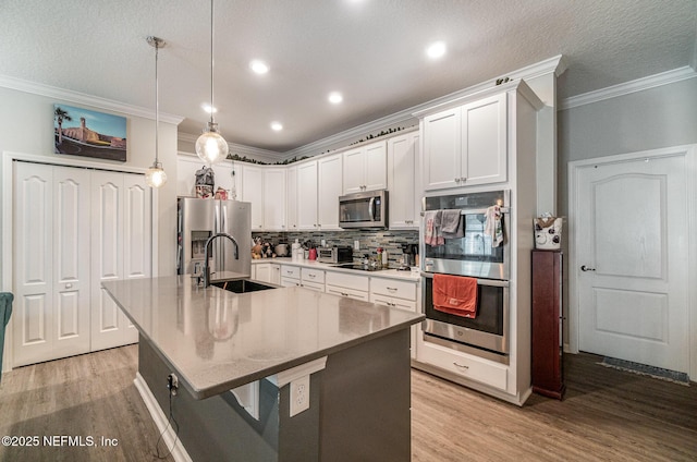 22 Sandstone Dr, Saint Augustine, FL 32086 - kitchen featuring appliances with stainless steel finishes, crown molding, light wood-style flooring, tasteful backsplash, and an island with sink