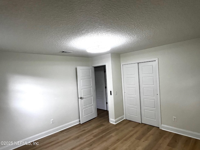 523 Eloise St, Macclenny, FL 32063 - unfurnished bedroom with dark wood-style flooring, a closet, and a textured ceiling