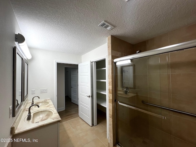 523 Eloise St, Macclenny, FL 32063 - bathroom with a shower stall, double vanity, a textured ceiling, and tile patterned flooring