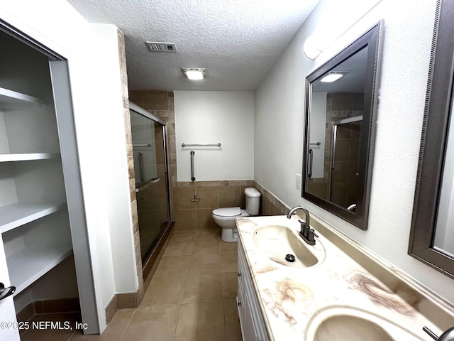 523 Eloise St, Macclenny, FL 32063 - bathroom with tile patterned floors, a stall shower, double vanity, a textured ceiling, and tile walls