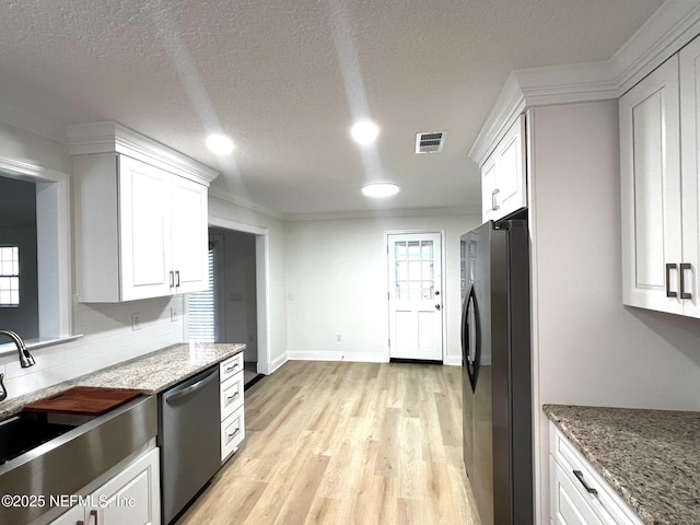 523 Eloise St, Macclenny, FL 32063 - kitchen featuring stainless steel appliances, white cabinetry, light wood finished floors, plenty of natural light, and crown molding
