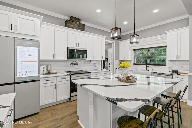 1926 Friendly Pl, Middleburg, FL 32068 - kitchen featuring stainless steel appliances, a kitchen breakfast bar, tasteful backsplash, wood finished floors, and white cabinets