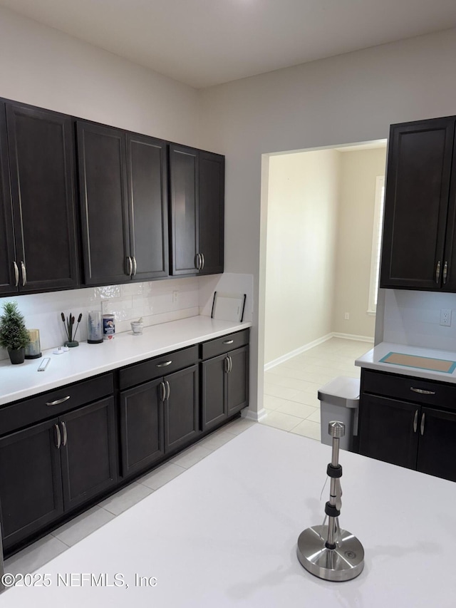 30139 Trophy Trl, Bryceville, FL 32009 - kitchen featuring light countertops, dark cabinetry, light tile patterned flooring, and backsplash