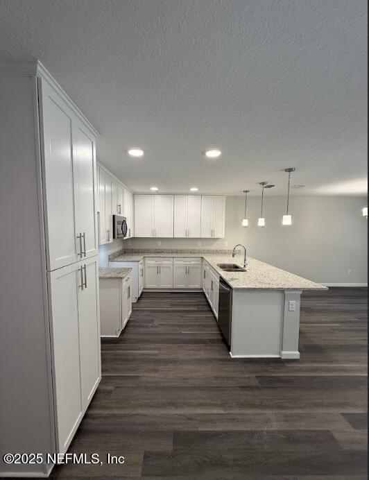 3138 Phyllis St, Jacksonville, FL 32205 - kitchen featuring a peninsula, dishwashing machine, white cabinets, a textured ceiling, and dark wood-style flooring
