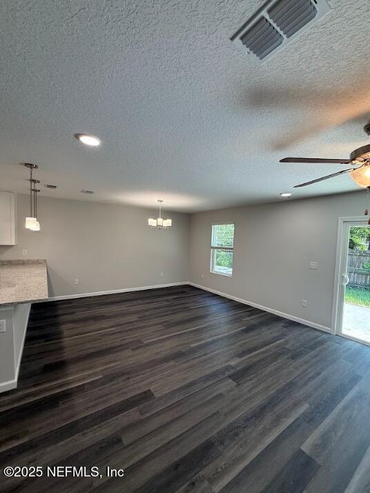 3138 Phyllis St, Jacksonville, FL 32205 - unfurnished living room with a ceiling fan, a textured ceiling, dark wood finished floors, healthy amount of natural light, and a chandelier