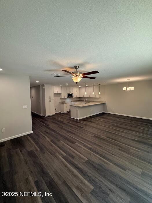 3138 Phyllis St, Jacksonville, FL 32205 - unfurnished living room featuring a textured ceiling, dark wood-type flooring, a chandelier, a ceiling fan, and recessed lighting