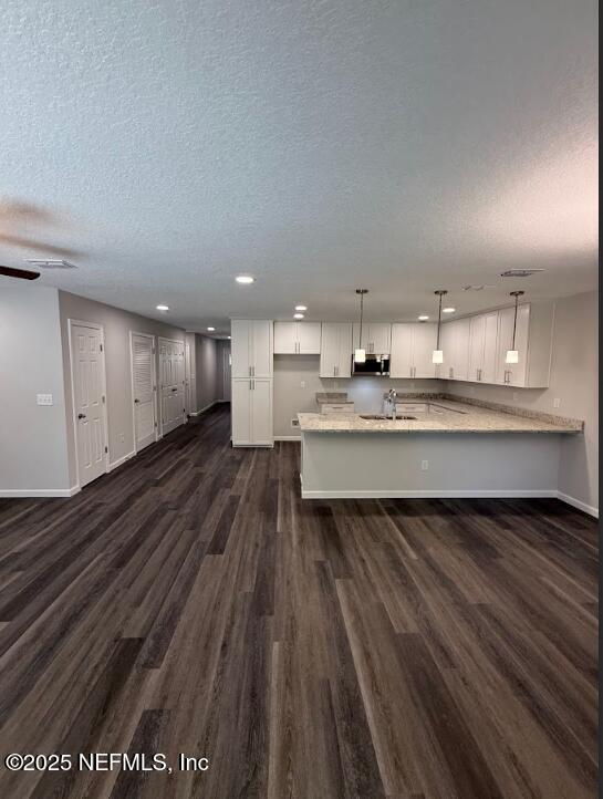 3138 Phyllis St, Jacksonville, FL 32205 - kitchen with stainless steel microwave, recessed lighting, dark wood finished floors, a peninsula, and white cabinetry