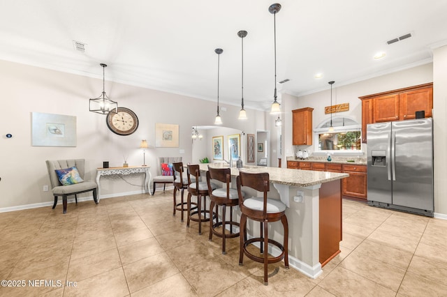 338 Deerfield Glen Dr, Saint Augustine, FL 32086 - kitchen with stainless steel fridge with ice dispenser, brown cabinets, crown molding, light tile patterned floors, and a breakfast bar