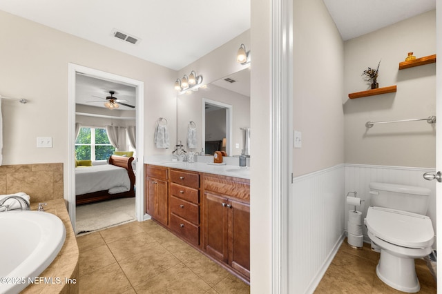 338 Deerfield Glen Dr, Saint Augustine, FL 32086 - full bath featuring double vanity, a bath, tile patterned floors, wainscoting, and a ceiling fan