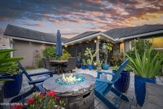 338 Deerfield Glen Dr, Saint Augustine, FL 32086 - patio terrace at dusk featuring a fire pit, outdoor dining area, and a patio area