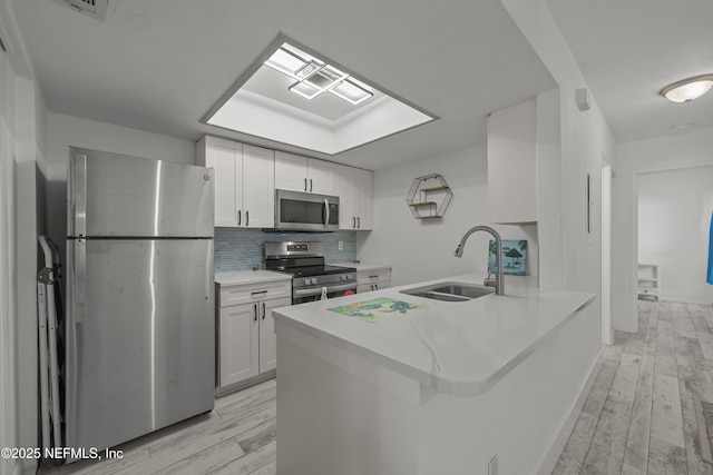 1206 Mayport Landing Cir, Jacksonville, FL 32233 - kitchen featuring appliances with stainless steel finishes, a peninsula, light wood-type flooring, and white cabinetry