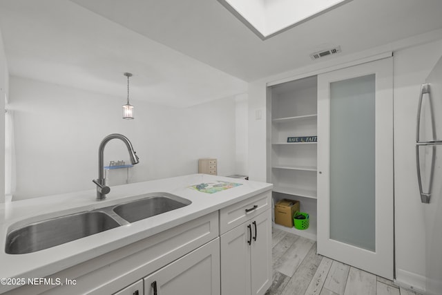 1206 Mayport Landing Cir, Jacksonville, FL 32233 - kitchen with light countertops, hanging light fixtures, white cabinets, light wood-type flooring, and freestanding refrigerator