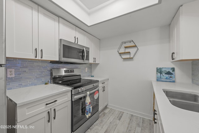 1206 Mayport Landing Cir, Jacksonville, FL 32233 - kitchen featuring appliances with stainless steel finishes, light wood-style floors, white cabinets, and decorative backsplash