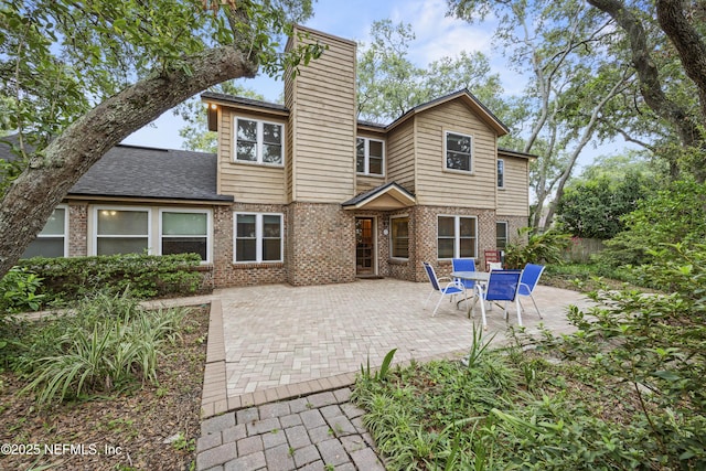 521 Birch Ct, Neptune Beach, FL 32266 - back of property featuring a chimney, brick siding, a patio area, and a shingled roof