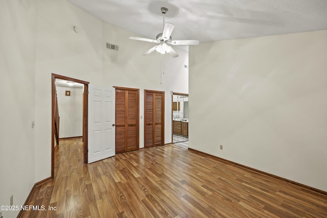 521 Birch Ct, Neptune Beach, FL 32266 - unfurnished bedroom with high vaulted ceiling, wood finished floors, two closets, connected bathroom, and a ceiling fan