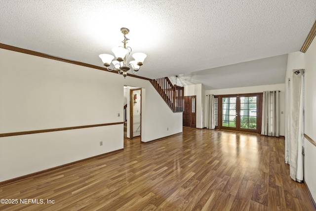521 Birch Ct, Neptune Beach, FL 32266 - unfurnished living room with a chandelier, a textured ceiling, wood finished floors, and stairway
