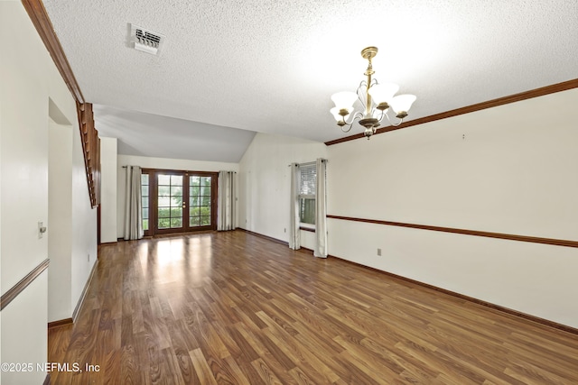 521 Birch Ct, Neptune Beach, FL 32266 - empty room featuring a chandelier, wood finished floors, lofted ceiling, and a textured ceiling