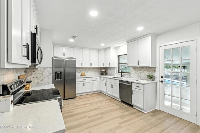 1900 Dalamon St, Jacksonville, FL 32211 - kitchen featuring stainless steel appliances, white cabinetry, light wood-style flooring, backsplash, and recessed lighting