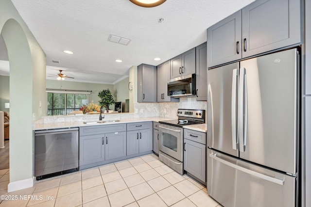 9745 Touchton Rd Unit 121, Jacksonville, FL 32246 - kitchen with appliances with stainless steel finishes, gray cabinets, decorative backsplash, arched walkways, and ceiling fan