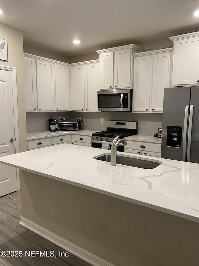66 Tree Frog Way, Saint Augustine, FL 32095 - kitchen with stainless steel appliances, white cabinetry, wood finished floors, light stone counters, and recessed lighting