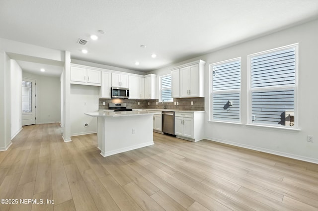 81 Glenhurst Ave, Ponte Vedra, FL 32081 - kitchen with appliances with stainless steel finishes, a kitchen island, white cabinetry, light countertops, and tasteful backsplash
