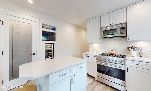 3793 Forest Dr, Middleburg, FL 32068 - kitchen with stainless steel appliances, wine cooler, light wood finished floors, white cabinetry, and recessed lighting