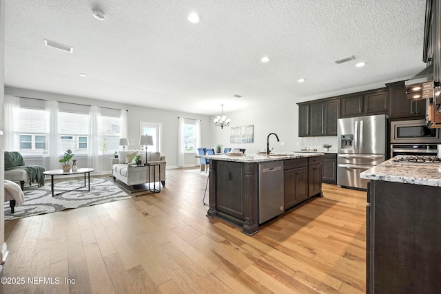 24 Tradesman Ln, Saint Johns, FL 32259 - kitchen featuring stainless steel appliances, a textured ceiling, dark brown cabinetry, light wood finished floors, and a chandelier