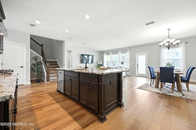 24 Tradesman Ln, Saint Johns, FL 32259 - kitchen with stainless steel dishwasher, a chandelier, a textured ceiling, light wood-style flooring, and dark brown cabinets