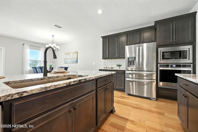 24 Tradesman Ln, Saint Johns, FL 32259 - kitchen with stainless steel appliances, light wood-type flooring, a chandelier, light stone countertops, and a textured ceiling