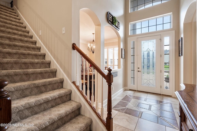 2025 Castle Point Ct, Fleming Island, FL 32003 - entryway featuring inlaid floor details, arched walkways, stairway, a chandelier, and a high ceiling